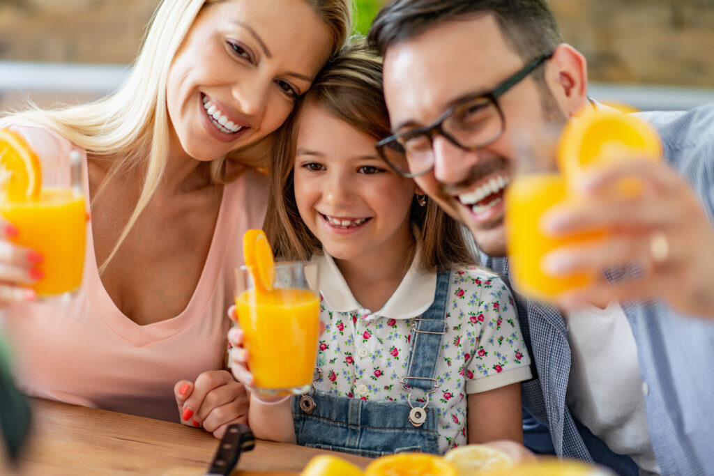 Eine junge Familie genießt ihren Orangensaft dank Fructaid®